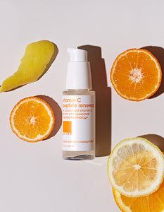 Skincare product surrounded by wheels of orange and lemon slices.