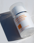 Small sized bottle on white background with a sharp shadow to its left.