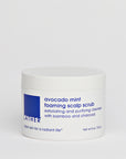 A white jar of Avocado Mint Foaming Scalp Scrub with blue label text, placed against a plain background.