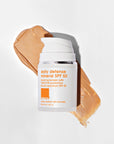 Daily Defense Mineral SPF 50 Facial Sunscreen bottle in front of swatch of tinted sunscreen product.