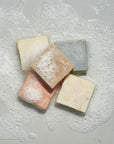Variety of LATHER bar soaps stacked in sudsy water
