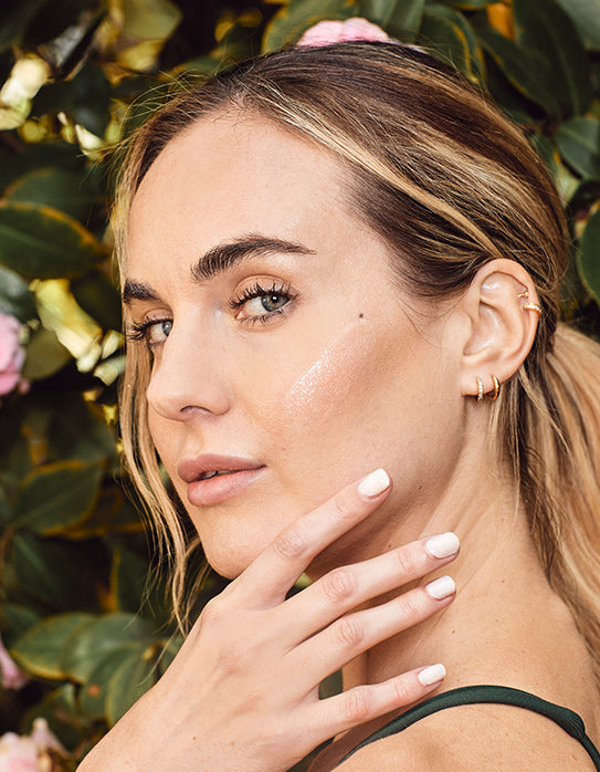 Woman with swatch of serum on her cheek bone
