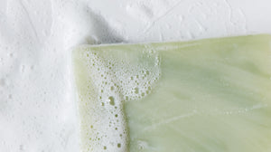 Close up image of LATHER Lavender Lime Soap Bar, in soft suds.