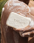 Person holding a bar of soap with soapy hands and back