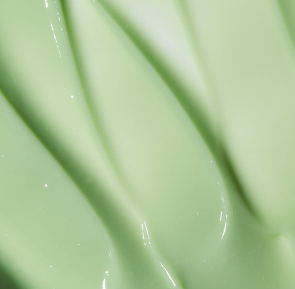 A close-up texture shot of smooth, glossy light green Avocado Mint Hair Repair with elegant swirled ridges.