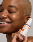 Woman hold white product by the side of her cheek.