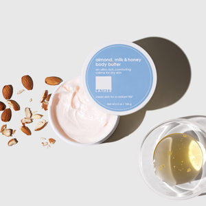 jar of body butter opened pictured next to almonds and bowl of oil