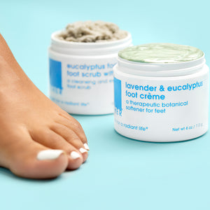 A model foot with Lavender and Eucalyptus Foot Creme and Eucalyptus Foaming Foot Scrub in background